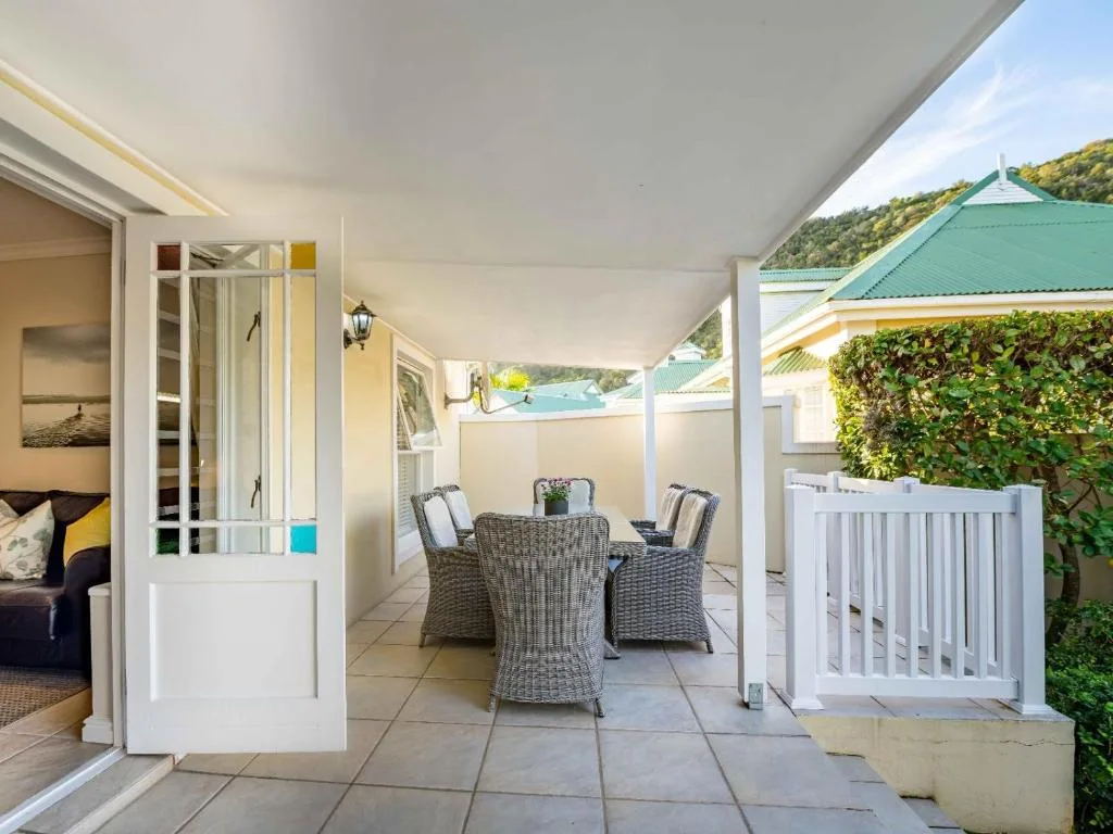 Covered patio with wicker seating and lagoon views beyond