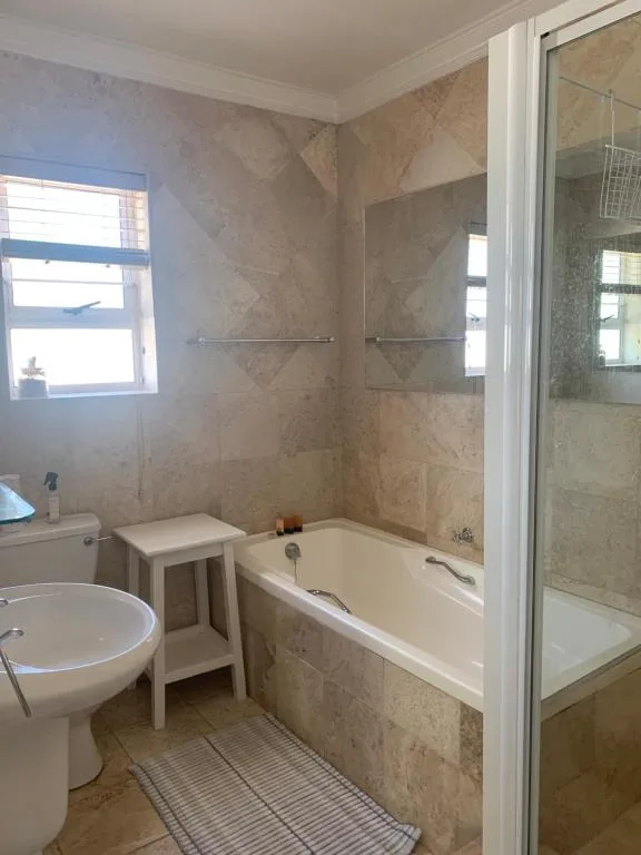 Modern bathroom with bathtub, shower enclosure, toilet, and marble tile finishes