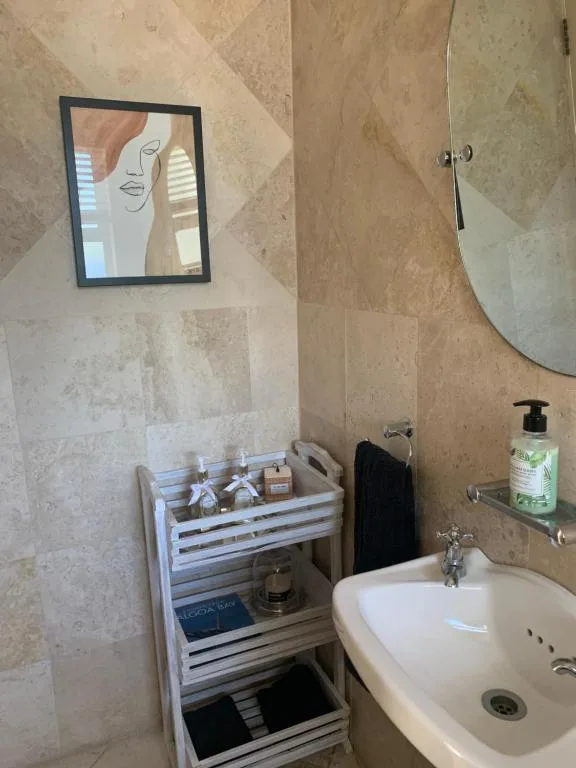 Modern bathroom with round mirror, white sink, and organized storage shelving