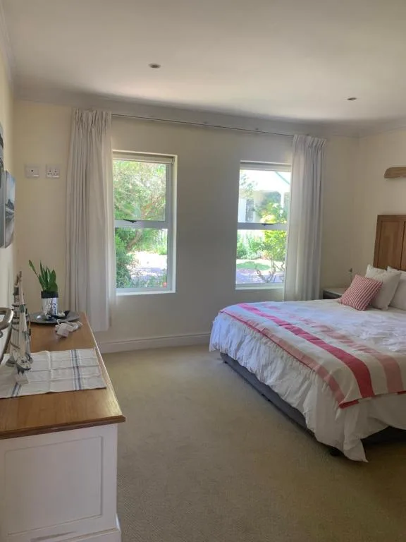 Bright bedroom with queen bed, large windows, and garden views