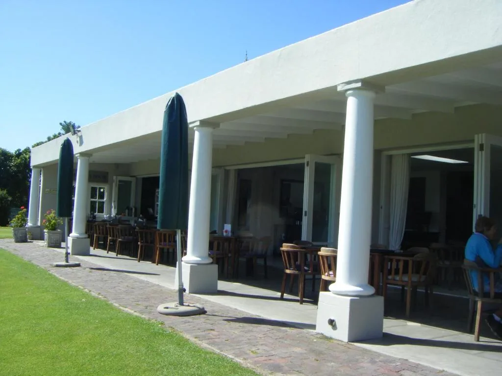 Modern covered patio with white columns, dining chairs, and ocean views
