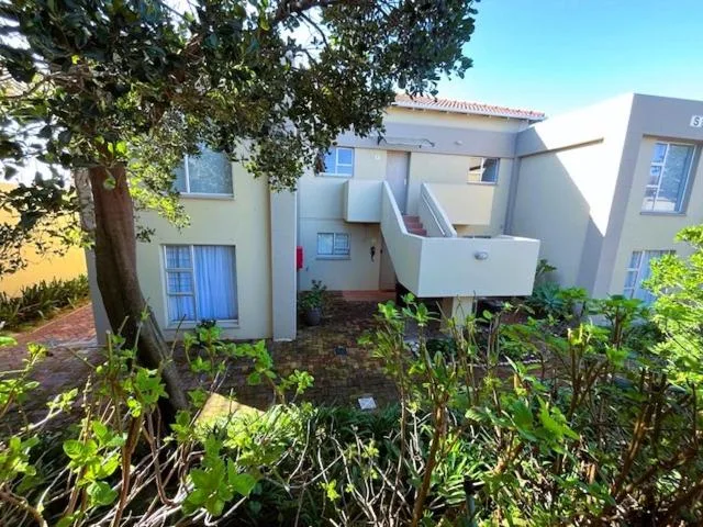 White modern apartment building with mature tree and garden landscaping