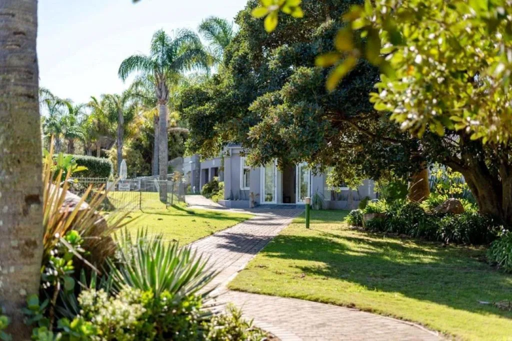 Modern white apartment building surrounded by lush green gardens and palm trees
