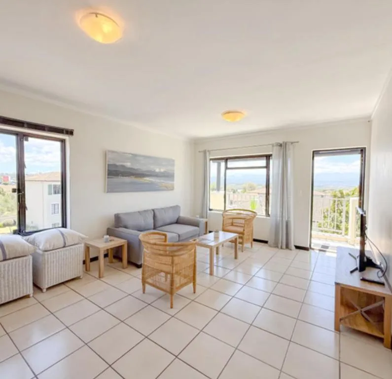 Spacious lounge with gray sofa, wooden chairs, and views of mountains and valley