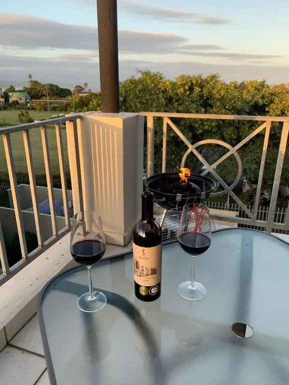 Elevated deck with wine glasses and bottle overlooking garden landscape at sunset