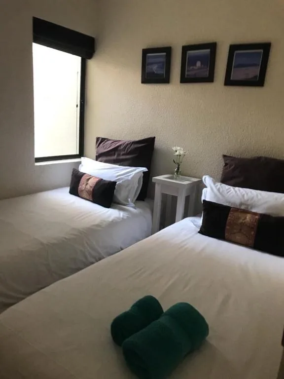 Bright bedroom with two twin beds, white linens, and framed artwork
