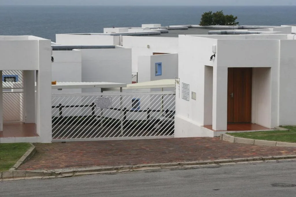 White modern apartment building with metal gate and ocean view backdrop