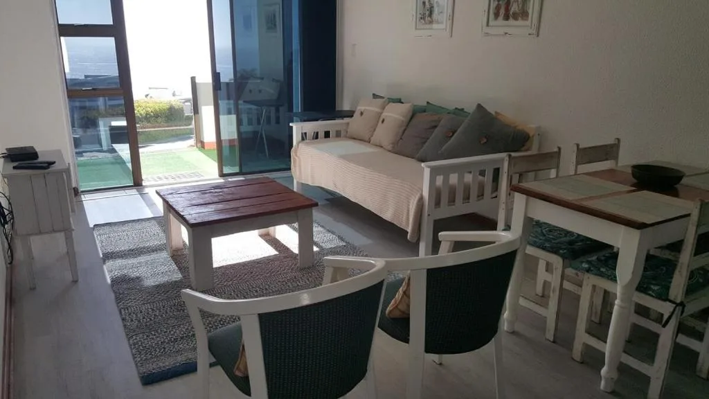 Open-plan lounge with sofa, coffee table, and ocean view through glass doors