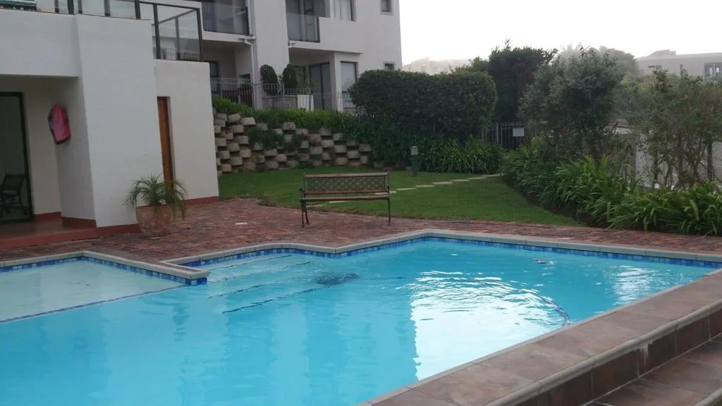 Sparkling blue swimming pool with brick patio and manicured gardens