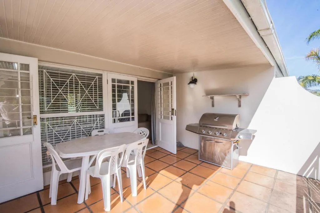 Covered patio with dining table, chairs, and braai grill