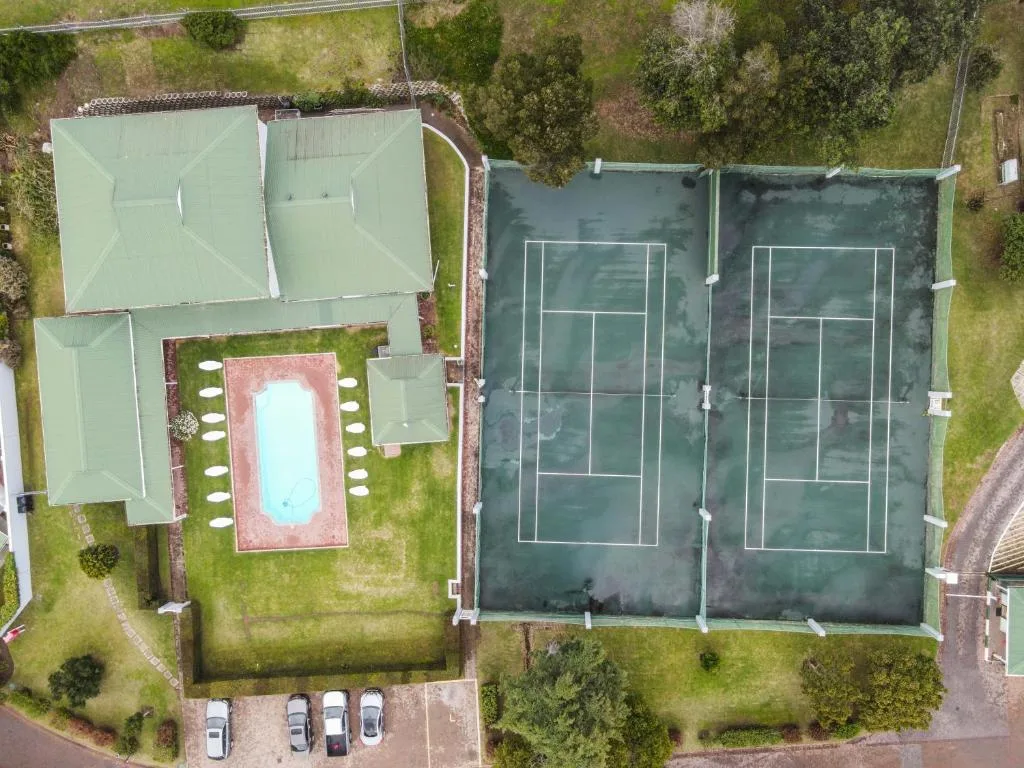 Aerial view of residential property with pool and tennis courts