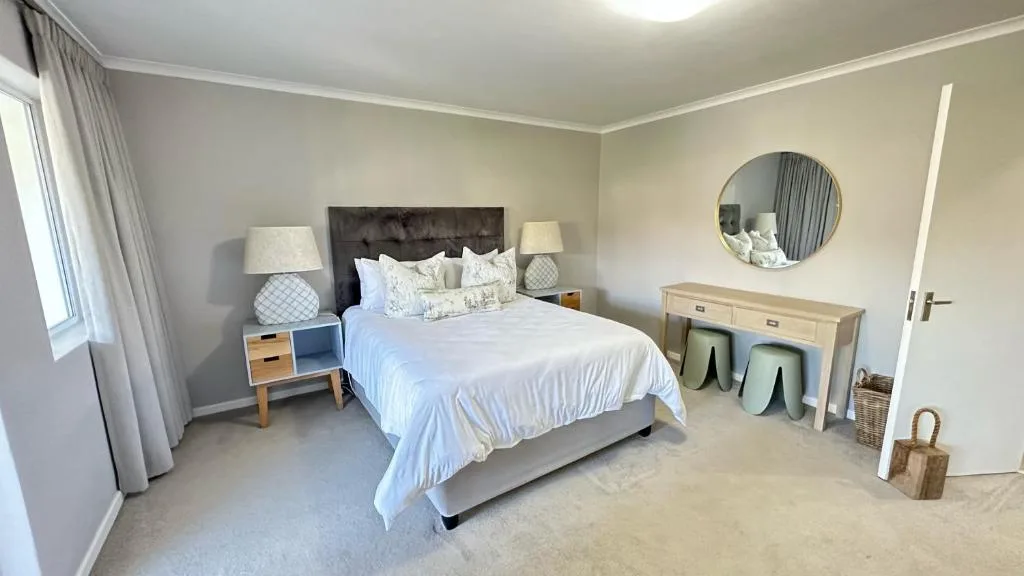 Spacious bedroom with queen bed, neutral decor, and natural light from windows