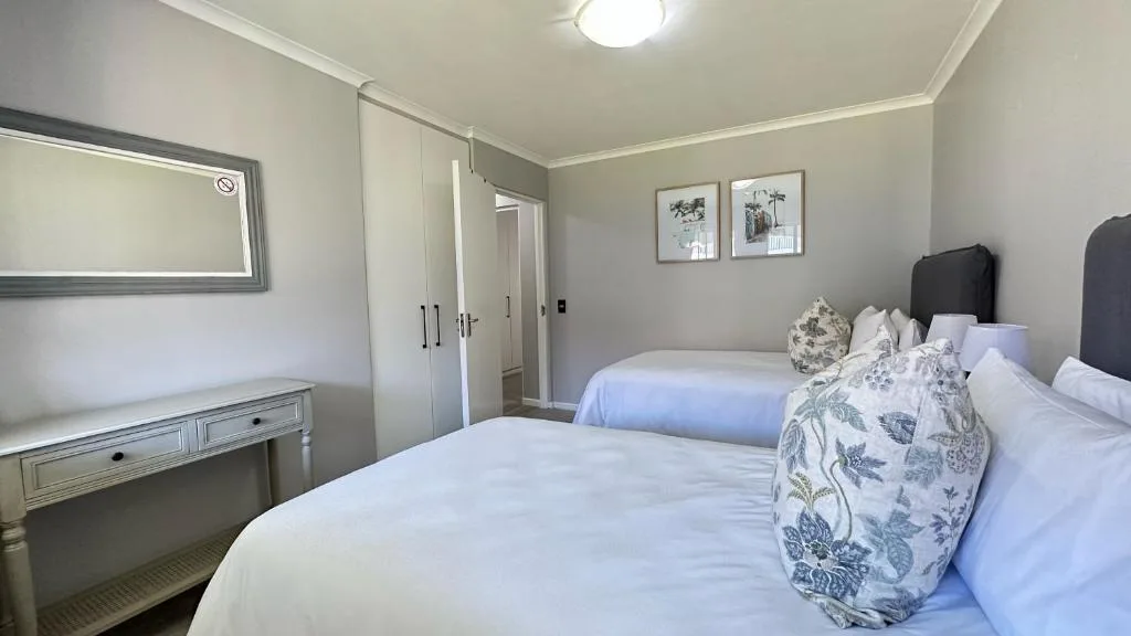 Bright bedroom with two beds, vanity mirror, and modern furnishings