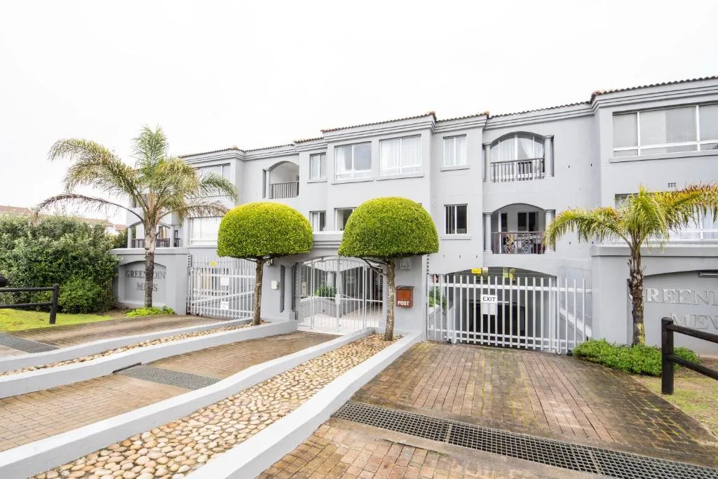 White townhouse complex with manicured topiary and secured entrance gate
