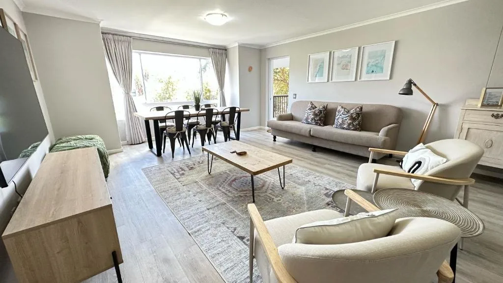Bright open-plan lounge with cream sofa, armchairs, and wooden coffee table