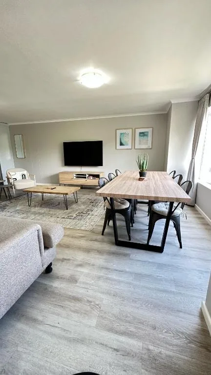 Open-plan lounge and dining area with TV, wooden table, and comfortable seating