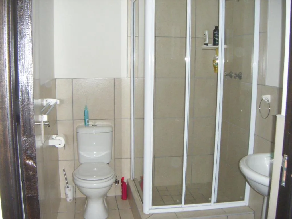 Bathroom with toilet, shower enclosure, and tiled walls