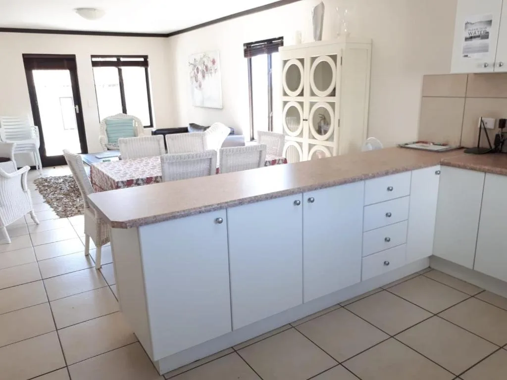 Open-plan kitchen with white cabinetry and granite countertop, dining area visible
