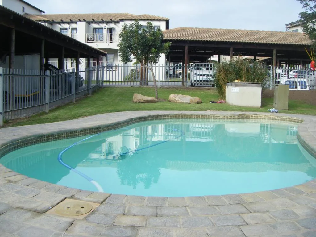Turquoise swimming pool with stone patio, main house and covered areas