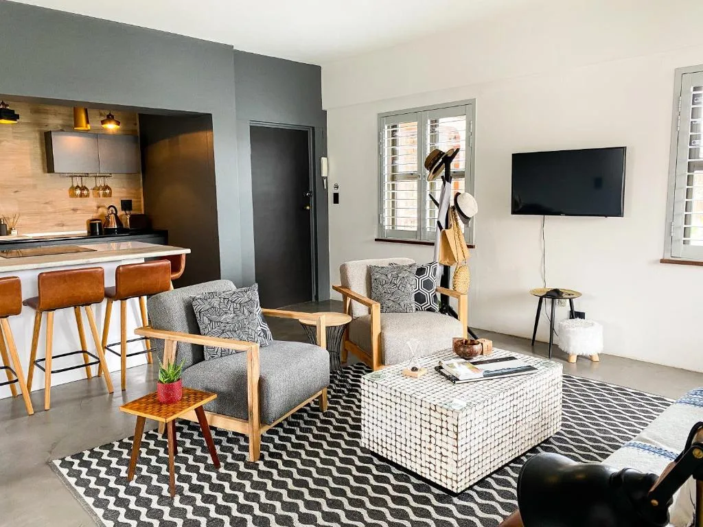 Modern living room with gray armchairs, white textured coffee table, and wall-mounted television