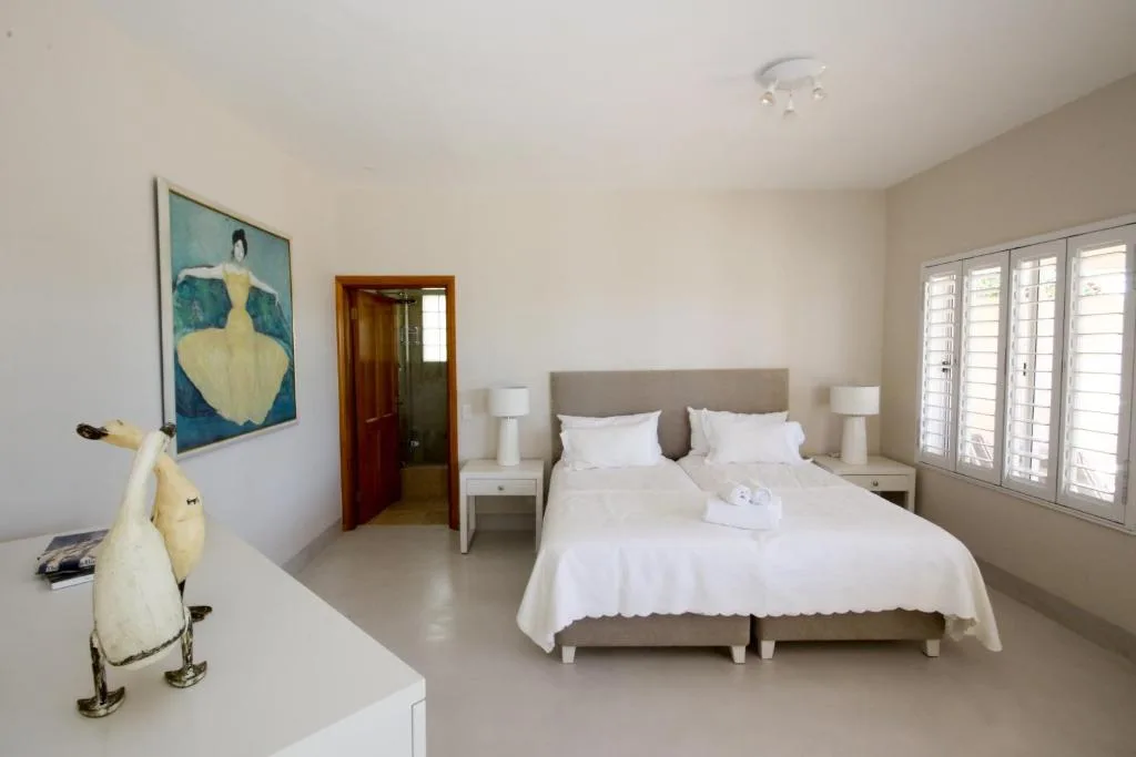 Spacious bedroom with king bed, taupe headboard, white bedding, modern décor