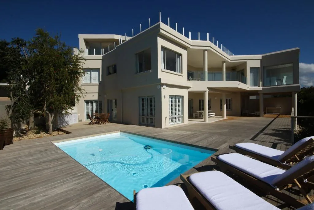 Modern luxury home with rectangular swimming pool and wooden deck loungers