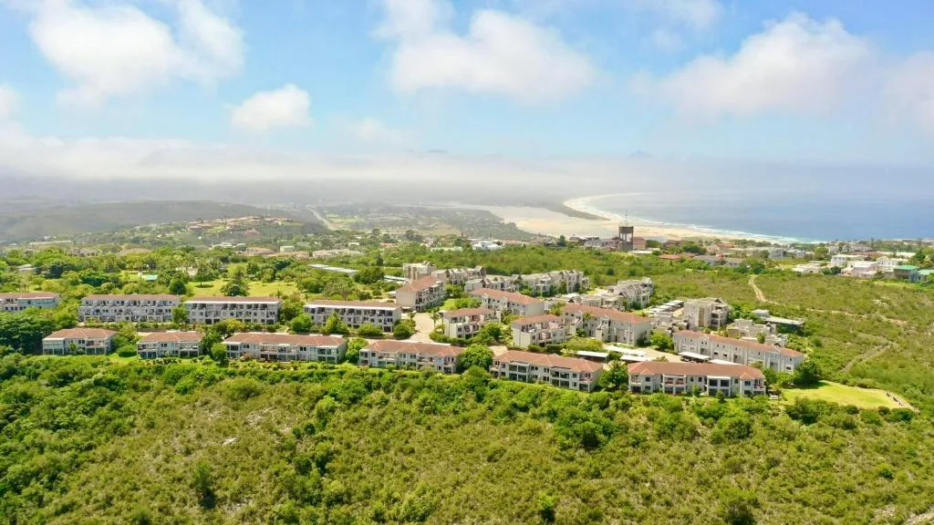 Aerial view of coastal town with beach and green hills beyond
