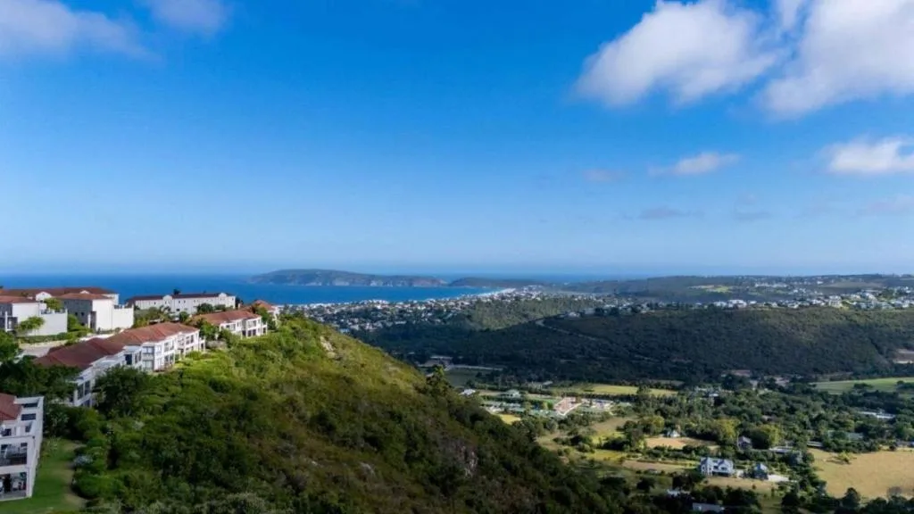 Panoramic coastal landscape with ocean, forested valleys, and distant cliffs