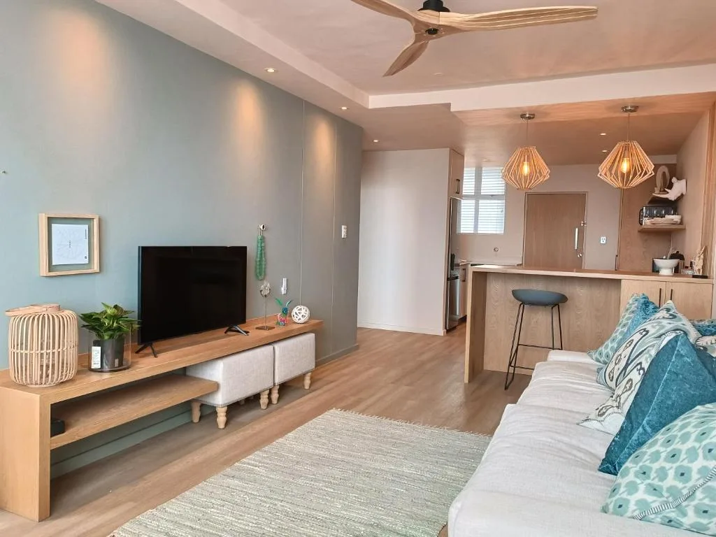 Modern lounge with TV, bed, kitchenette, and contemporary pendant lighting
