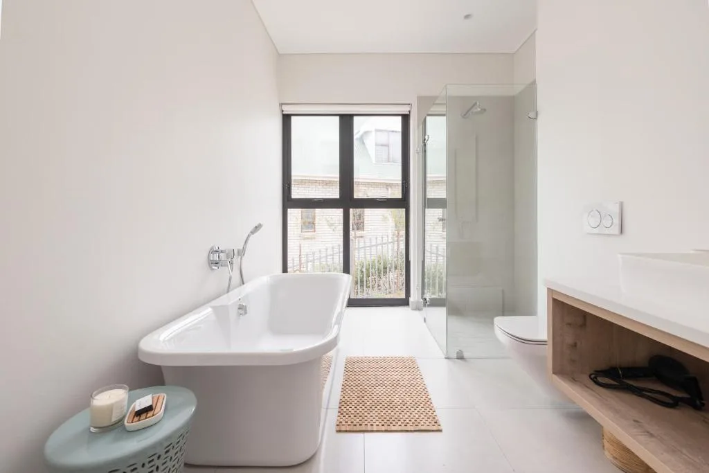 Modern bathroom with freestanding bathtub, glass shower, and ocean view doors