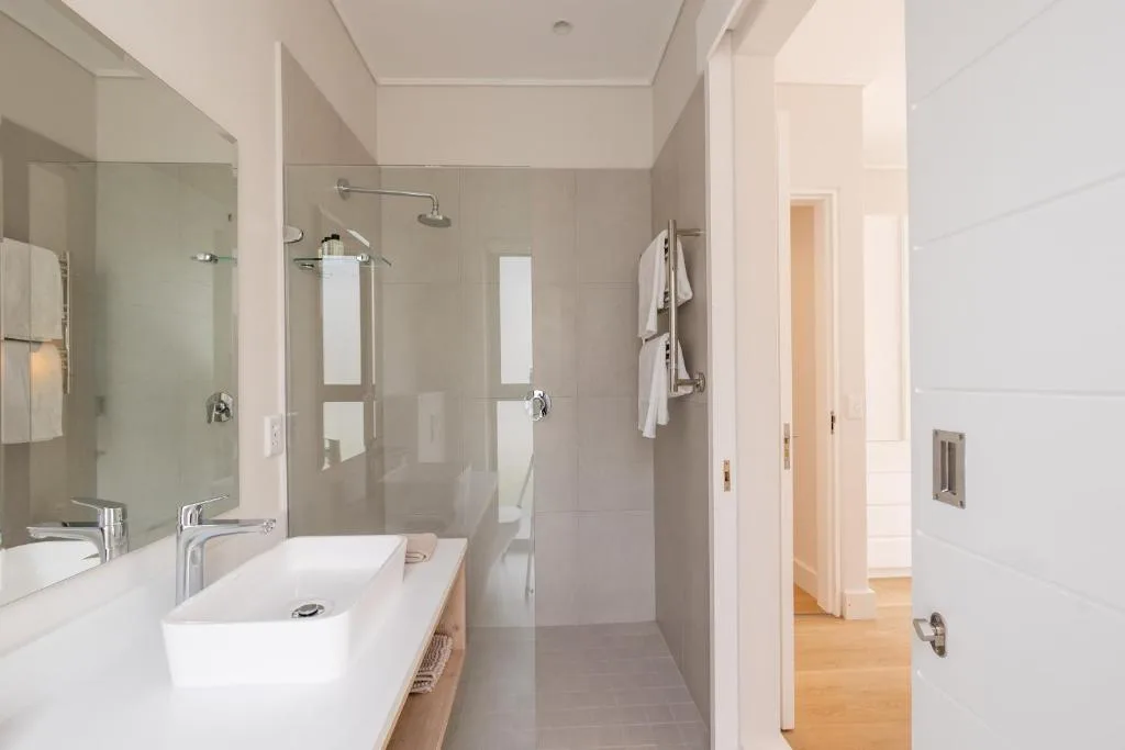 Modern bathroom with double vanity, walk-in shower enclosure, and natural light