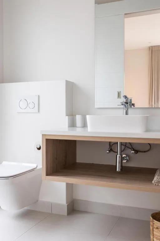 Modern bathroom with white vessel sink, toilet, and large mirror