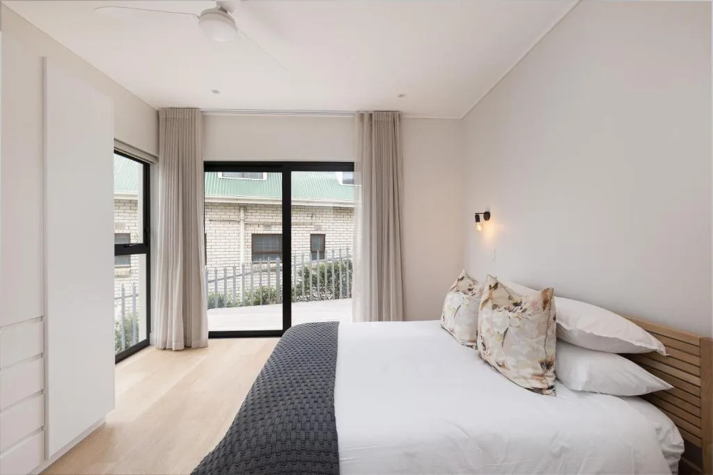 Bright bedroom with queen bed, glass doors opening to private deck area