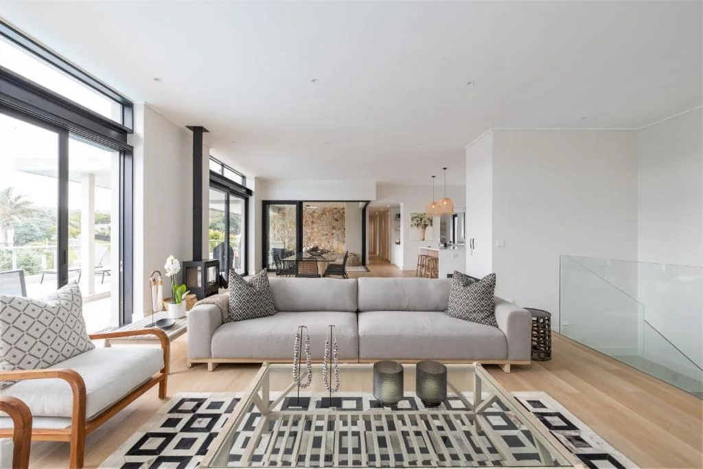 Modern living room with gray sofa, wooden armchair, and geometric patterned rug