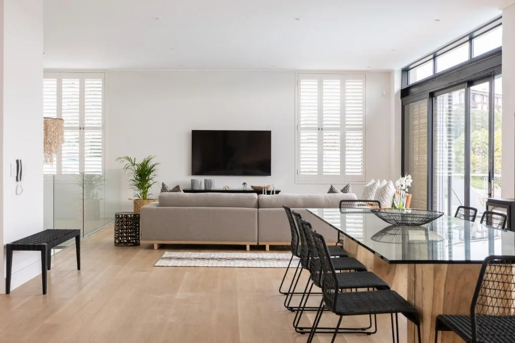 Modern lounge with gray sofa, wall-mounted TV, and large windows