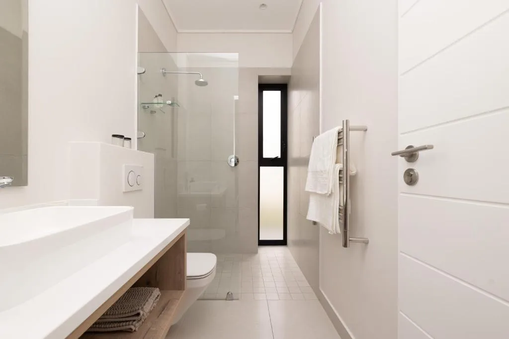 Modern bathroom with walk-in shower, white vanity, and heated towel rack