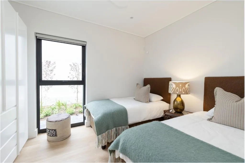 Twin bedroom with brown headboards, white bedding, and garden view doors