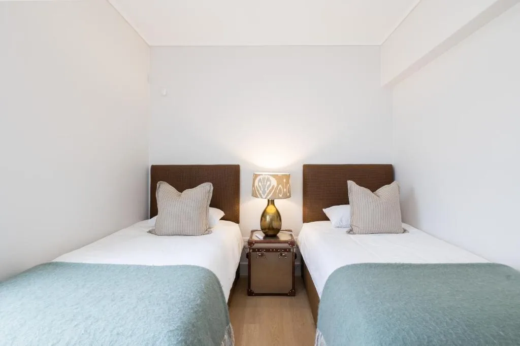 Twin bedroom with white walls, wooden headboards, and turquoise blankets