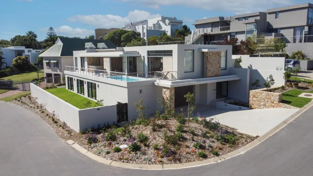 Modern white villa with pool, landscaped garden, and garage entrance