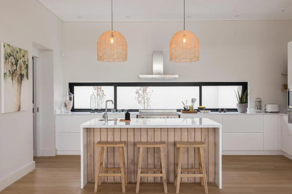Modern kitchen with white cabinetry, island with wooden stools, pendant lights