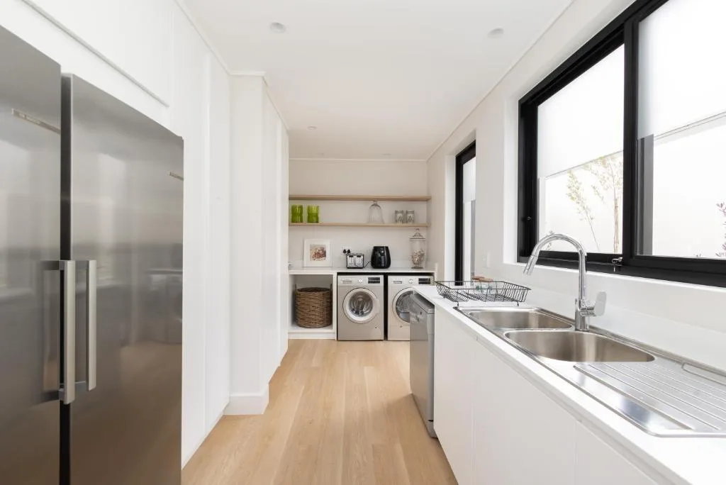 Modern galley kitchen with stainless steel sink, appliances, and laundry area