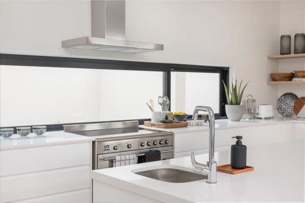 Modern white kitchen with stainless steel appliances and window view