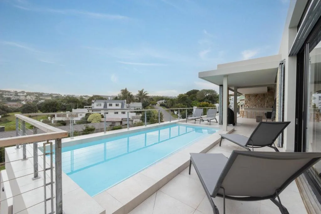 Modern swimming pool with loungers overlooking Plettenberg Bay landscape