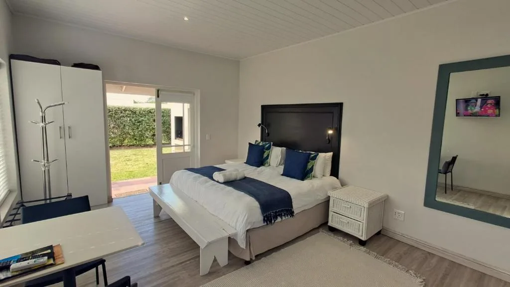 Bright bedroom with queen bed, navy accents, wardrobe, garden views