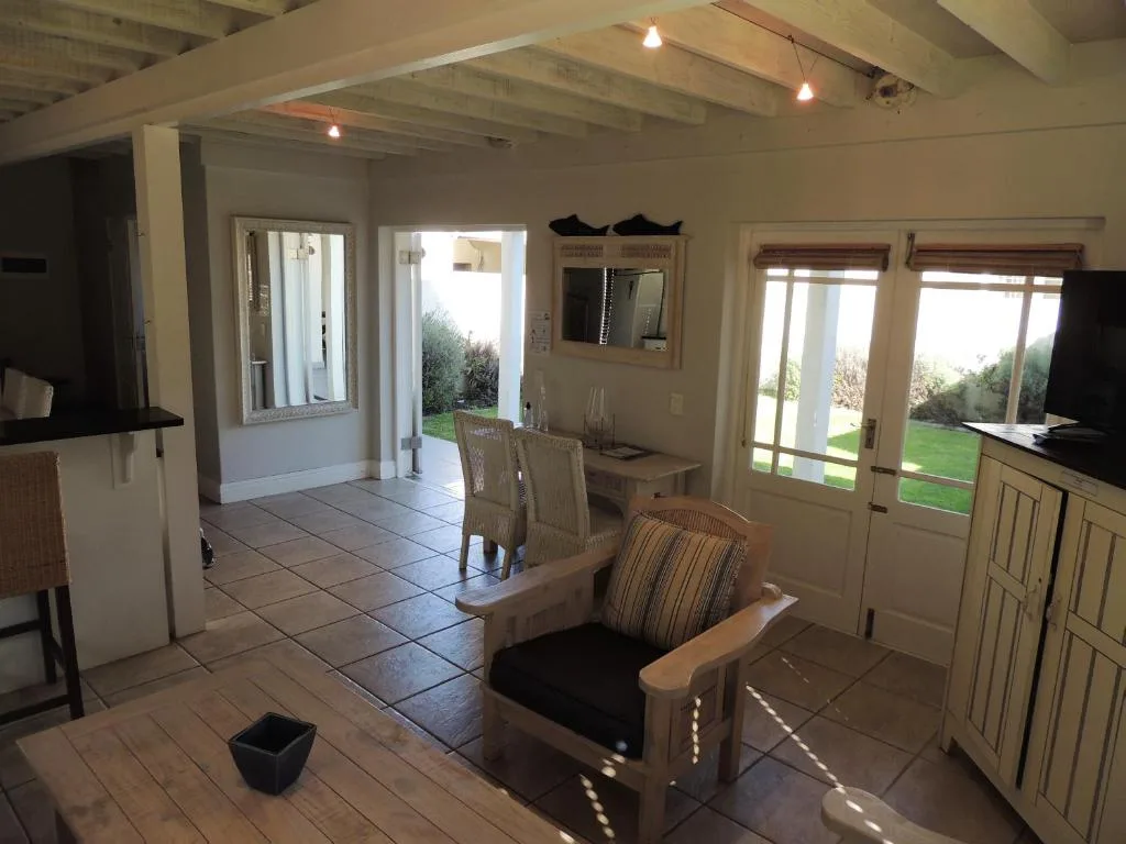 Open-plan lounge with armchair, exposed beams, and garden views