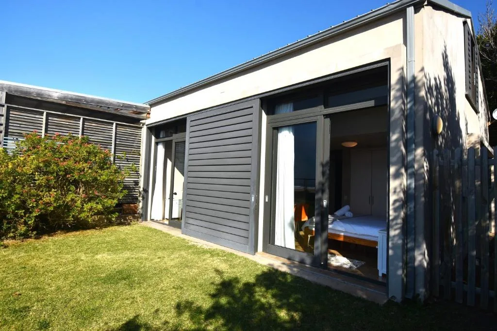 Modern dark-clad holiday home with large glass doors and manicured lawn garden