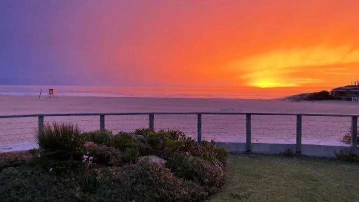 Stunning sunset over the ocean with coastal landscape and railing