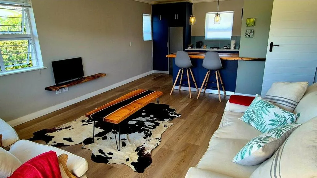 Open-plan lounge with cream sofa, wooden bench, and kitchen area visible