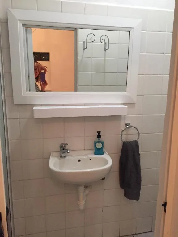 Small bathroom with wall-mounted sink, mirror cabinet, and towel rack