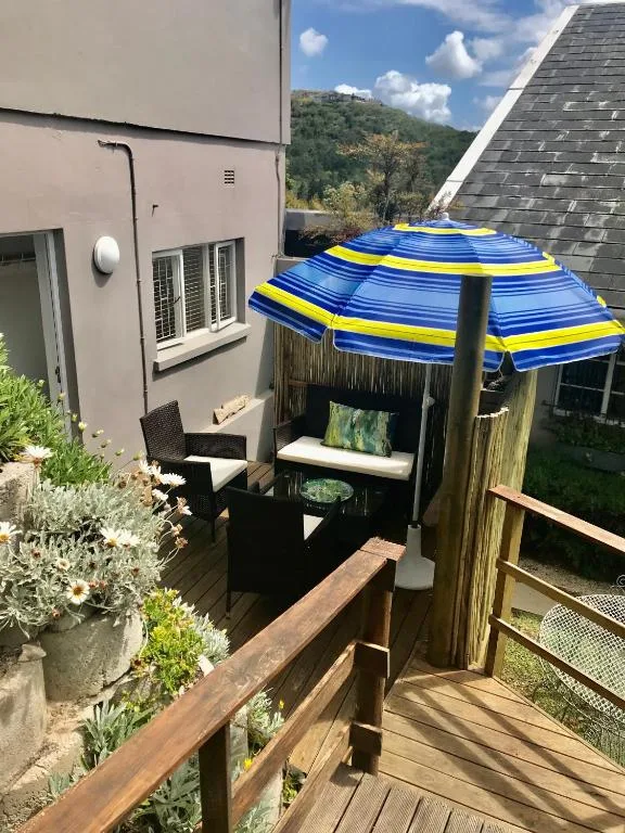 Wooden deck with striped blue umbrella and black seating chairs